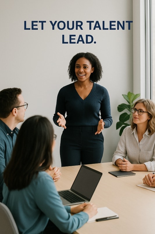 A confident African American woman stands at the head of a modern conference table, leading a team meeting with expressive hand gestures. Four diverse colleagues sit around the table, listening attentively. Above her, the bold caption reads, “LET YOUR TALENT LEAD.” The setting is bright and professional, with natural light and minimalist décor. ChatGPT fragen